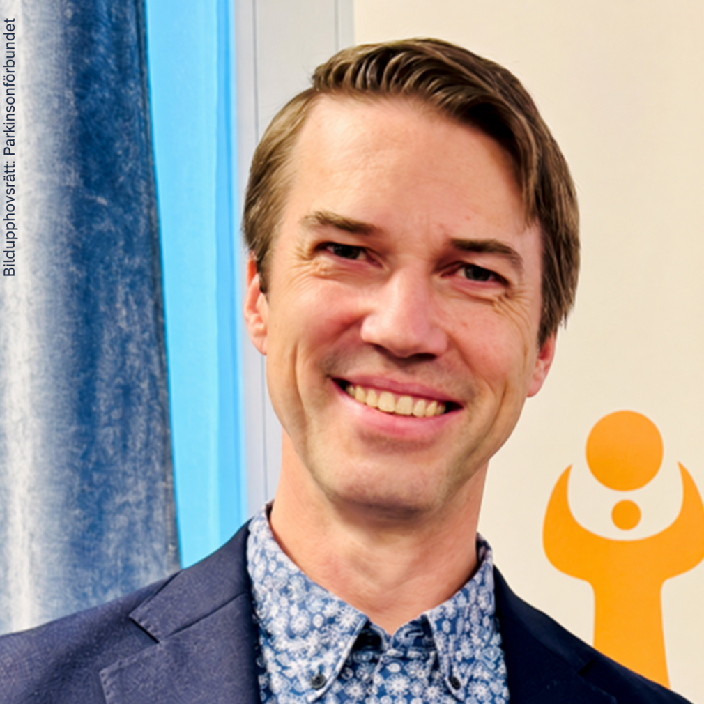 Leende man framför orange logotyp