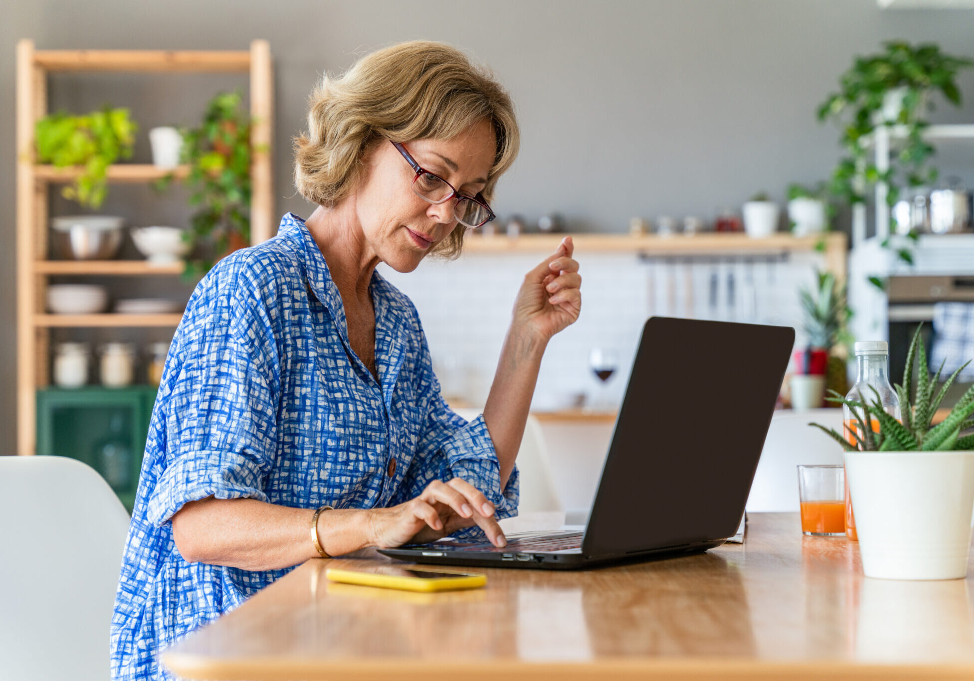 Beautiful mature senior woman at home, domestic life and leisure moments - 50-60 years old pretty female adult remote working with computer laptop